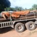 A flatbed truck carrying stacked construction materials parked on a dirt road.