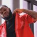 Liberian rapper Bucky Raw poses in a red jacket during a photoshoot, highlighting his public image amid ongoing discussions about mental health and his legal troubles.