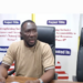 A man seated at a conference table speaking during an Integrity Watch Liberia press briefing on the proposal to add 14 new legislative seats.