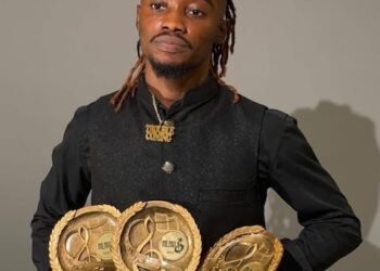 Liberian artist King Dennis holding multiple MLMA 2025 award trophies after winning major categories.