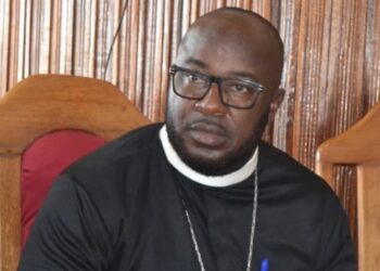 Rev. F. Philip L. Nushann Jr. seated indoors during the national Access to Justice conference, wearing clerical attire and speaking on justice reform initiatives.