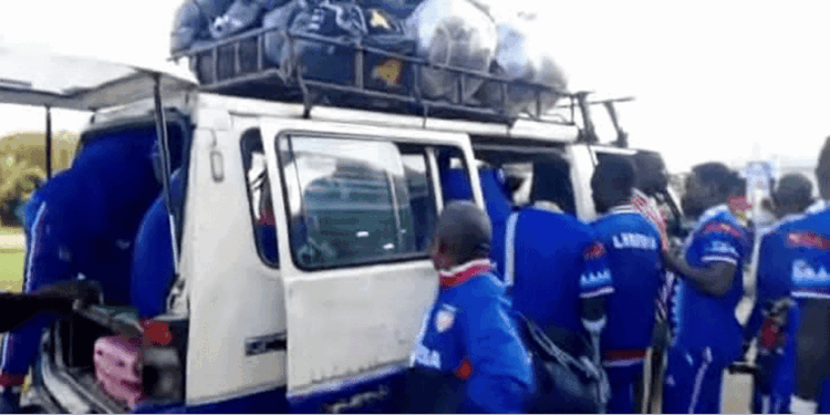 Members of Liberia’s amputee football team boarding a crowded commercial bus with luggage tied on the roof after returning from a tournament.