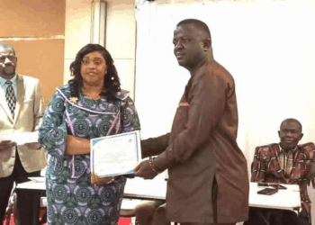 Nimba County education officials present certificate to newly added volunteer teacher during payroll induction ceremony.