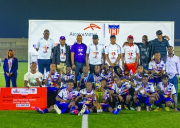 imba District #8 football team and officials pose with the championship trophy, medals, and a ceremonial check after winning the 2025 ArcelorMittal Cup in Ganta.