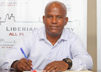 Wubetu Abate seated at a desk signing his contract as the new head coach of LISCR FC