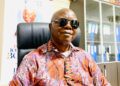 A man wearing sunglasses and a patterned shirt seated in an office, identified as UP Margibi fundraising chair Ben A. Fofana.