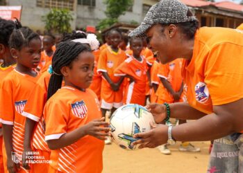 LFA official hands a football to a young girl during the launch of a girls’ football development campaign in Paynesville.