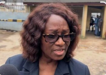 A woman speaking to the media outside a public building in Monrovia following a procurement dispute involving the NEC.