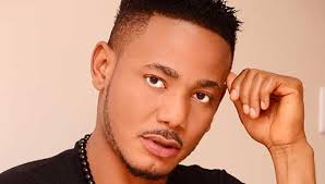 Liberian actor Gregory Artus wearing a blue suit jacket and white shirt posing for a studio portrait