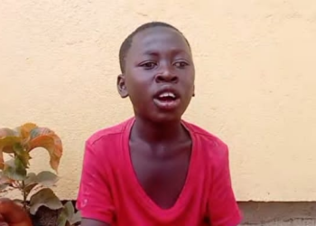 Visually impaired teen Henry Joe in a red shirt speaking in Gbartala, Bong County, as he appeals for support to return to school.