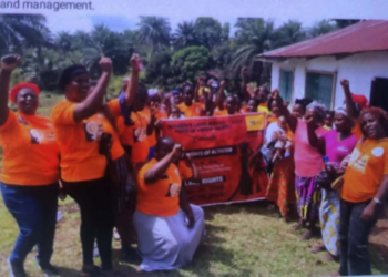 Group of women wearing orange shirts gathered outdoors holding a banner during a Women’s Land Rights Taskforce awareness event