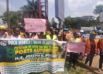 Dock workers protest at Capitol Hill holding a banner urging President Boakai to veto port autonomy bills