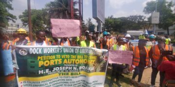 Dock workers protest at Capitol Hill holding a banner urging President Boakai to veto port autonomy bills