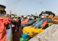 Liberian commuters at a Monrovia bus terminal as taxis and buses continue charging old fares despite the government’s October 2025 transport fare reduction.