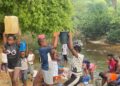 Residents of Morris Farm Community in Todee District, Rural Montserrado County, fetch water and wash clothes at a creek along the Du River due to limited access to hand pumps.