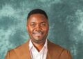 Cassell Kouh in brown jacket smiling