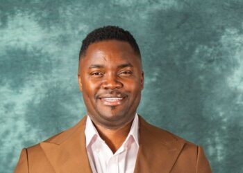 Cassell Kouh in brown jacket smiling