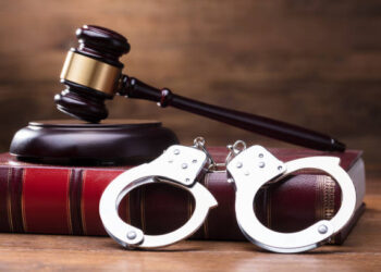 Gavel And Handcuffs On The Law Book Over The Wooden Table Background