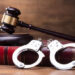 Gavel And Handcuffs On The Law Book Over The Wooden Table Background