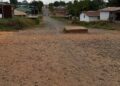 Unpaved road with dust and nearby homes in a Liberian community