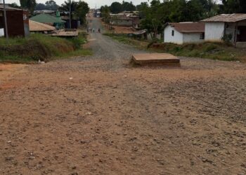 Unpaved road with dust and nearby homes in a Liberian community