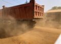 Dump truck raising heavy dust on unpaved road at Worlakor Junction in Mount Barclay