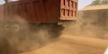 Dump truck raising heavy dust on unpaved road at Worlakor Junction in Mount Barclay
