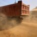 Dump truck raising heavy dust on unpaved road at Worlakor Junction in Mount Barclay