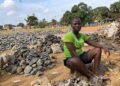 Woman sitting among crushed rocks in Monrovia informal work site