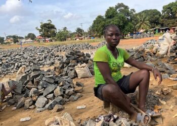 Woman sitting among crushed rocks in Monrovia informal work site
