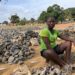 Woman sitting among crushed rocks in Monrovia informal work site