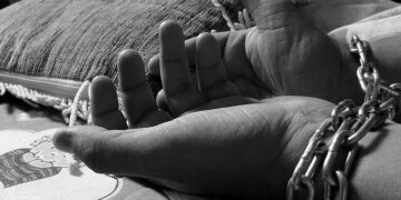 Illustration of restrained hands symbolizing human trafficking and exploitation following a grand jury indictment in Liberia.
