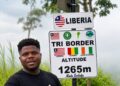 Ghanaian YouTuber Wodemaya standing at the Liberia-Guinea-Ivory Coast tripoint in Nimba County.