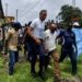Police escort Rep. Thomas Romeo Quioh through the University of Liberia’s Capitol Hill campus as students gather nearby
